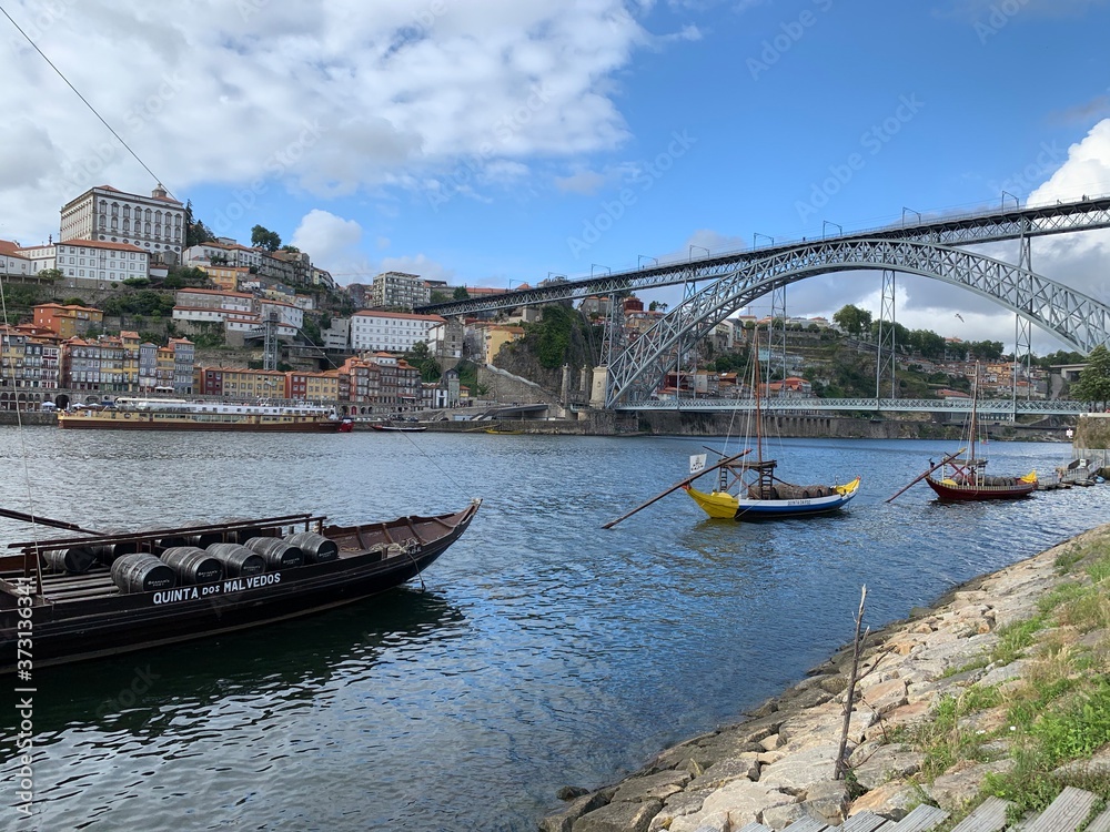 Dom Luis I bridge and traditional boats with wine barrels on Rio Douro river in Porto, Portugal