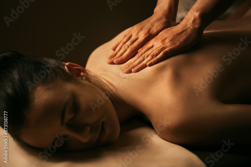 The beautiful girl has massage. Authentic image of luxury spa treatment. Warm colors, charming light.