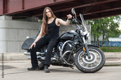 Long-haired guy on a black motorcycle under the bridge © Дэн Едрышов