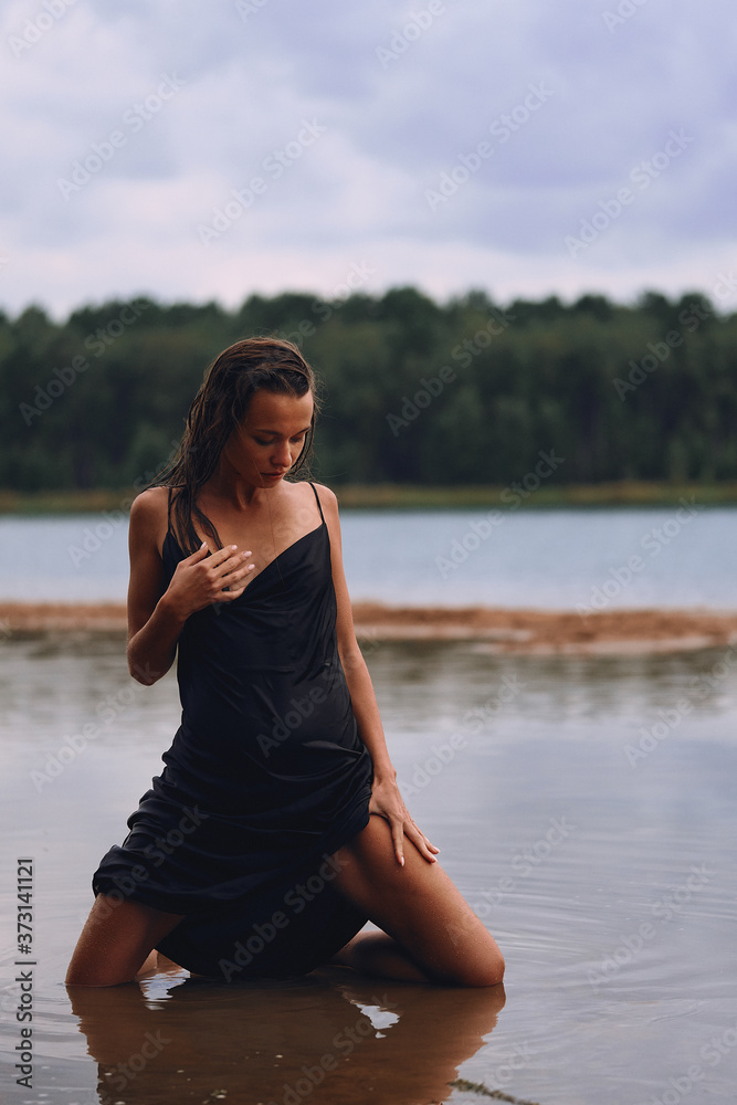 girl kneeling in a long black dress on the shore of the bay, the concept of the joy of health, sleep and relaxation girl kneeling in a long black dress on the shore of the bay, the concept of the joy of health, sleep and relaxation