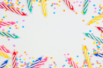 Colorful birthday cake candles with candy sprinkles. Top down view frame on a white background. Copy space.