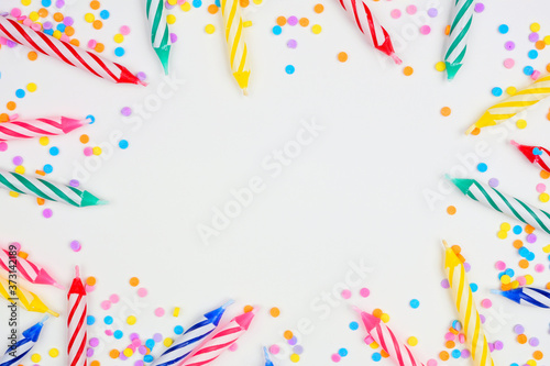 Colorful birthday cake candles with candy sprinkles. Top down view frame on a white background. Copy space.