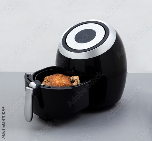 Air fryer machine with fried pork knuckle on white background