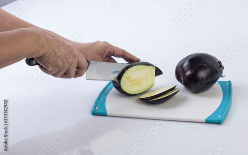 Housewife cutting eggplant with knife on a cutting board