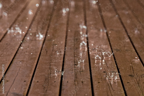 Rain from thunderstorm splash down on old worn wooden floor.