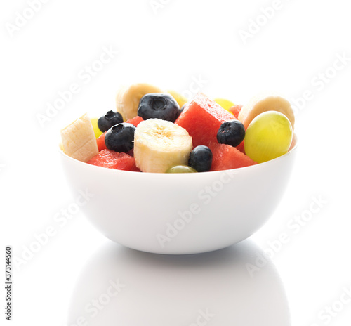 Fresh fruit salad on a plate on a white background, watermelon, grapes, banana and blueberries, close-up