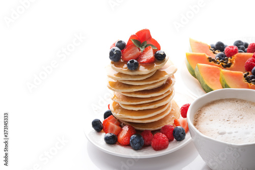 Breakfast with pancakes with berries and honey, coffee and fruit isolated on a white background, copy of space