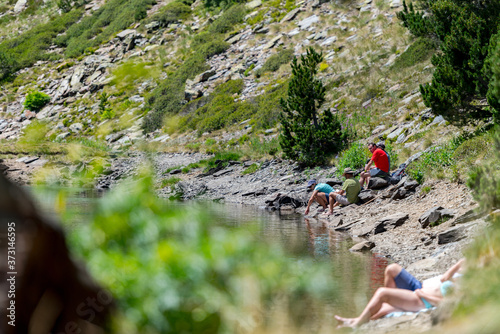 COMA PEDROSA, ANDORRA - Aug 07, 2020: Group of tourists resting at Lago de les Truites in Andorra Pyre photo