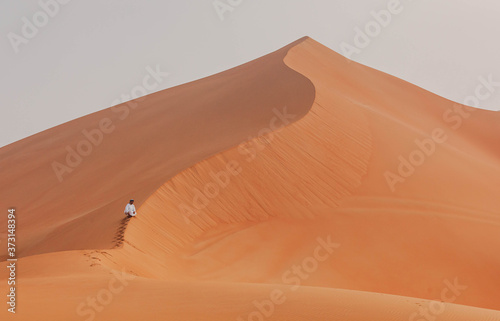 Emirati man climbing a dune in the empty quarter desert