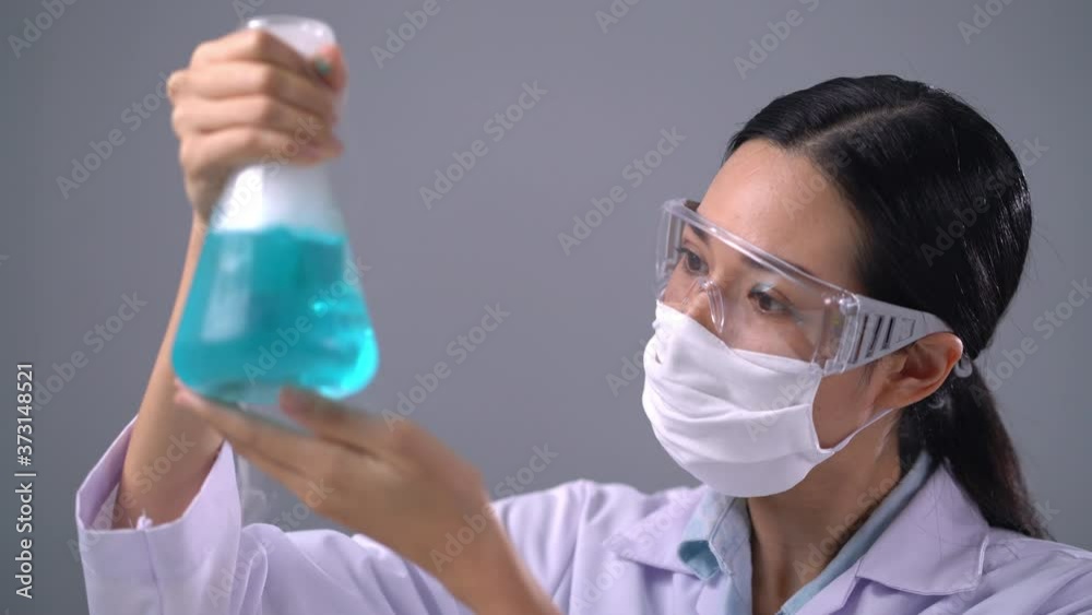 Expert woman scientist medical wearing a protective eyeglasses and safety medical mask holds a test tube