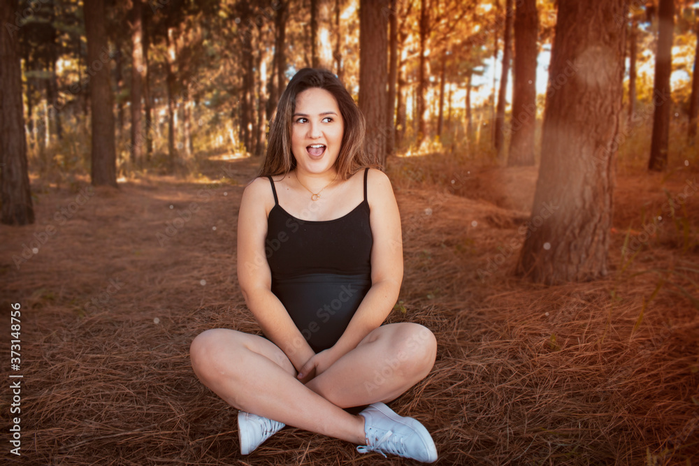 Pregnant woman smiling sitting on the floor of a pine field, hands on belly. Reddish autumn photo. Pregnant woman smiling sitting on the floor of a pine field, hands on belly. Reddish autumn photo.