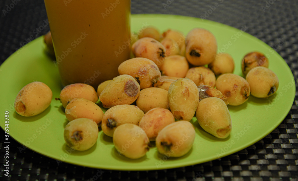Frozen fruits and loquat juice (Eriobotrya japonica) arranged on top of a green plate