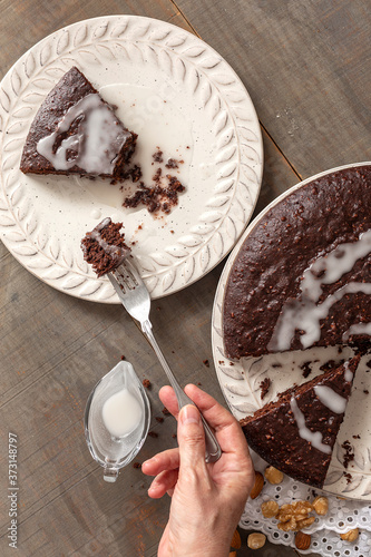 Cocoa homemade pie from above. A plate with a slice and a hand with a fork.