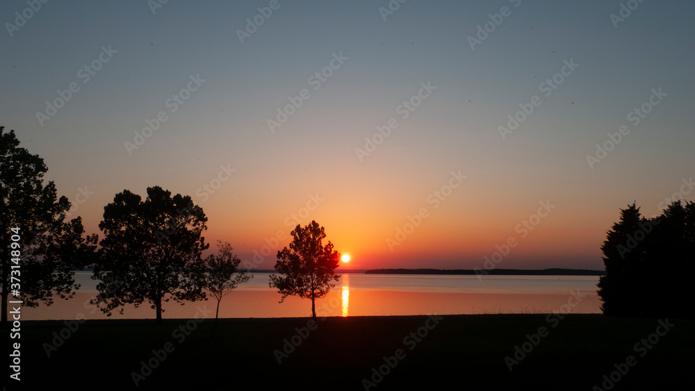Sunset on the lake with trees in silhouette