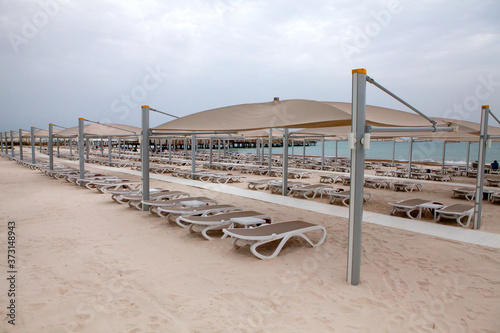 Beach with sun loungers umbrellas during rain on a rainy day