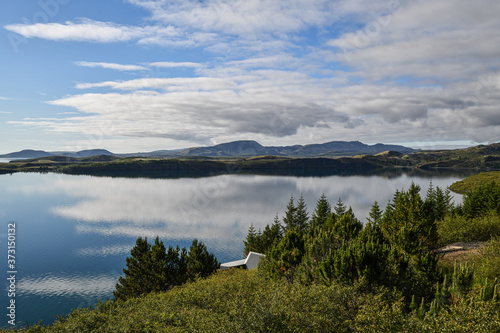 Islands spiegelglatte Seen mit Bergen im Hintergrund und blauem Himmel mit Wolken