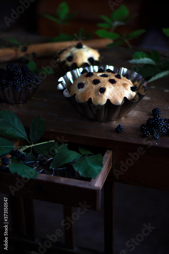 Delicious delicious pastries with berries on a vintage brown table with green BlackBerry branches. An open Desk drawer with a creative solution. Berry cake with blackberries. Dark mood