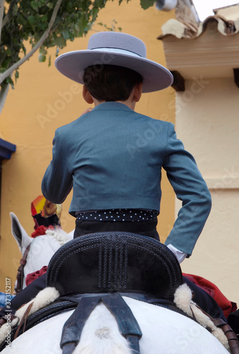 Niño vestido con traje campero subido a caballo en la Feria de Fuengirola photo