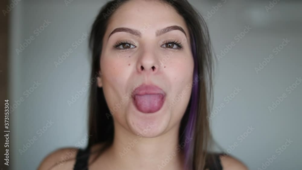 Pretty girl sticks tongue out. Young woman doing funny gesture showing tongue grimacing Pretty girl sticks tongue out. Young woman doing funny gesture showing tongue grimacing