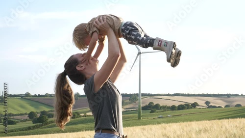 Cute mother and son play together in a field of wheat
