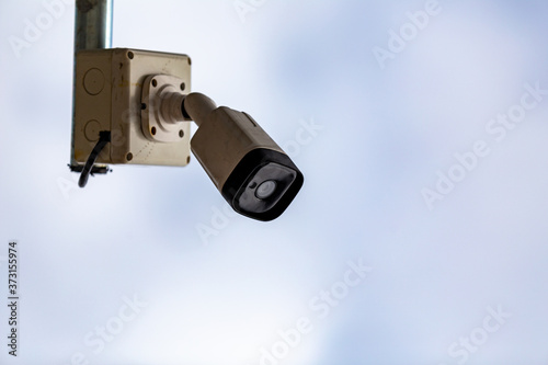 Old cctv cameras hanging on a pole, with sky background
