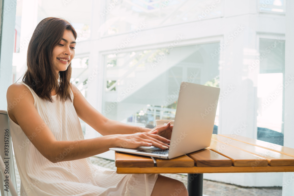 Young woman using laptop at coffee shop.