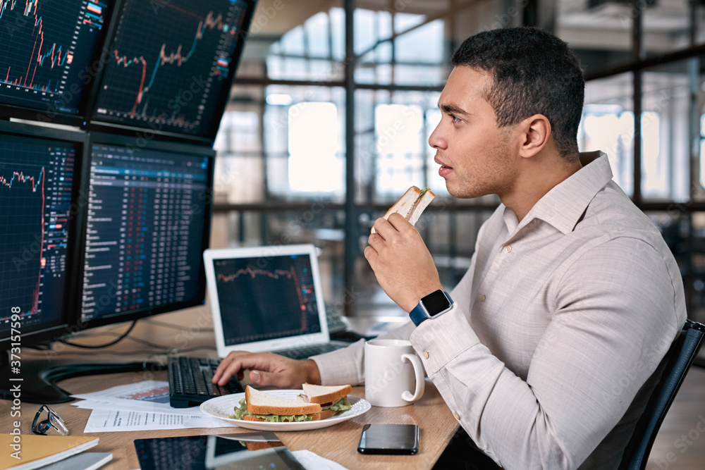 Stock Traiding. Trader sitting at office in front of monitors with data using trading bot make trades cryptocurrency exchange while having break eating sandwich and drinking coffee Stock Traiding. Trader sitting at office in front of monitors with data using trading bot make trades cryptocurrency exchange while having break eating sandwich and drinking coffee