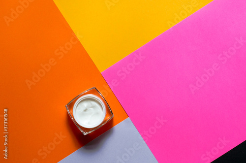 Jar of skin cream on a multi-colored paper background. Beauty concept. Minimalism.