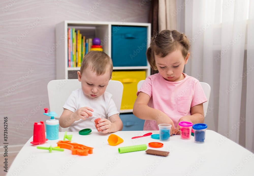 Fototapeta premium children develop fine motor skills playing with plasticine at the table in the room