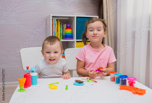happy children play with plasticine at the table in the room
