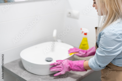 Cleaning - cleaning bathroom sink with spray detergent - housework, spring cleaning concept