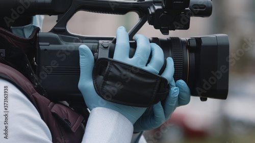 Close up, african black videographer with medikal mask looking through the viewfinder on video camera . High quality photo photo