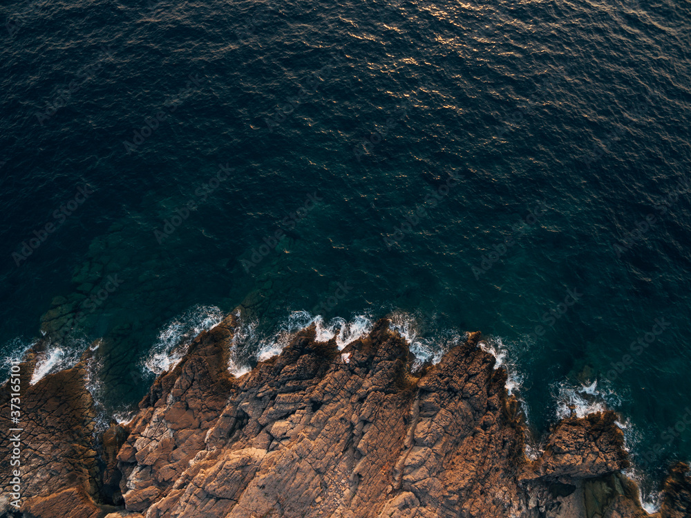 Rocky sea coast, waves hitting the rocks, aerial top view.