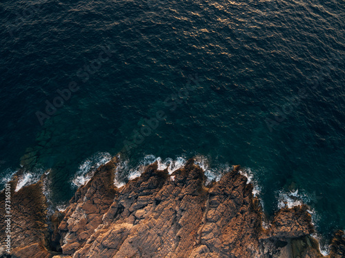 Rocky sea coast, waves hitting the rocks, aerial top view.