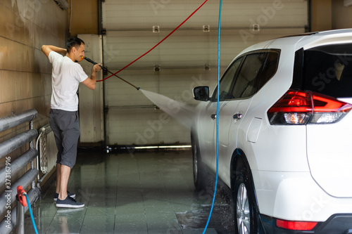 Young man spraying his car clean