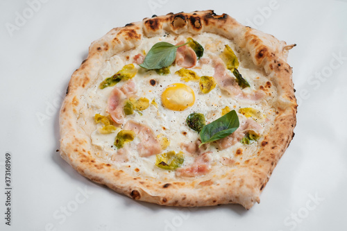 Italian pizza with egg, ham and basil on a white background.