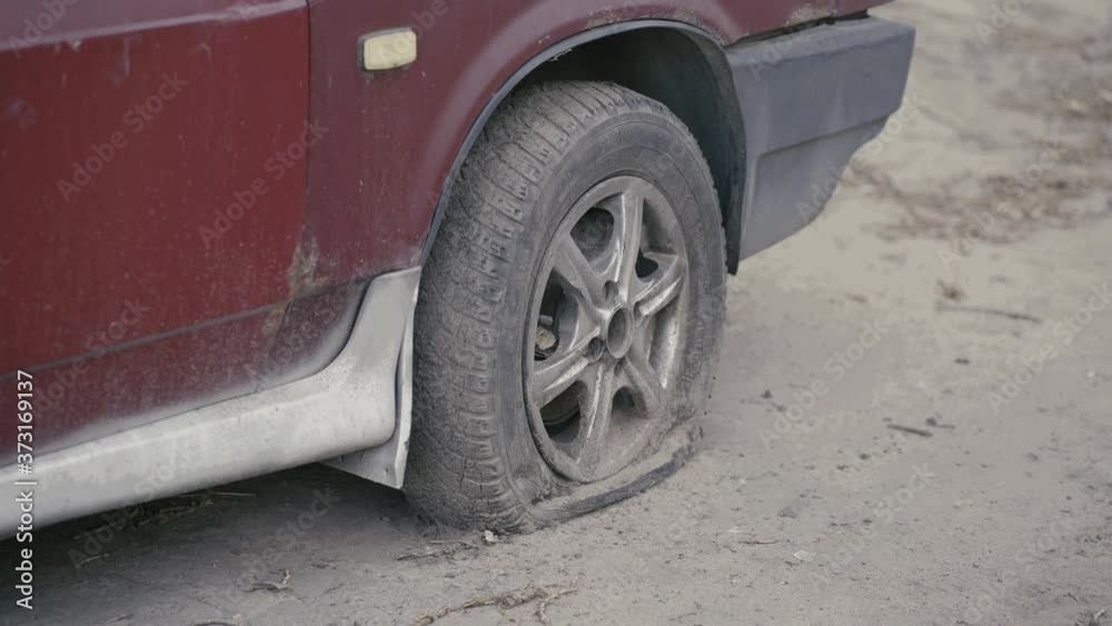Car with deflated wheel on street. Old red car with deflated wheel parked on paved street in sunlight. Car with deflated wheel on street. Old red car with deflated wheel parked on paved street in sunlight.
