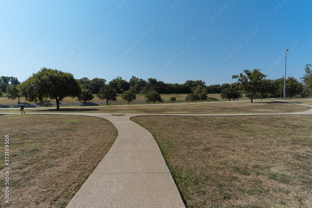 A concrete path in a Texas city park on a sunny August day.