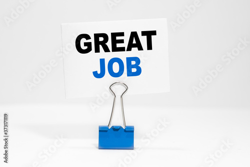GREAT JOB inscription on a white business card on a white endless background in a blue clip.