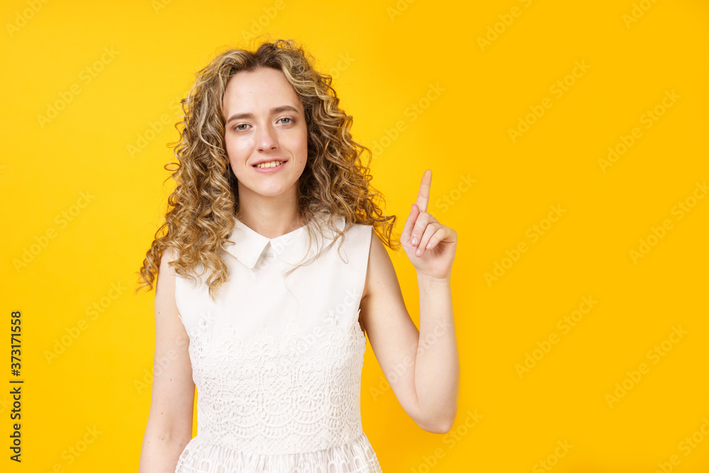 Portrait of a young smiling woman who raised her finger to the top. Female portrait.