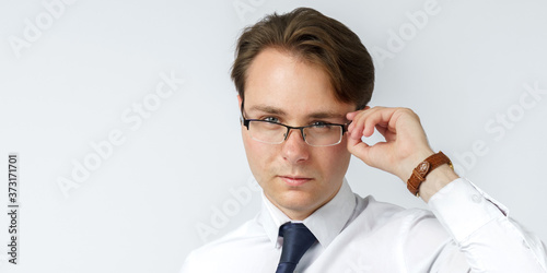 Portrait of a businessman adjusting his glasses. White background.