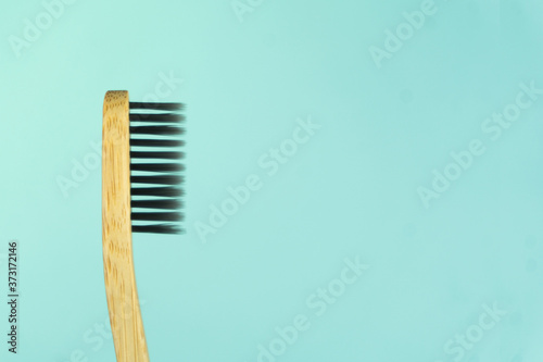 Close up of a bamboo toothbrush on the left side of the photo with a tiffany-colored background. No plastic. No waste. 