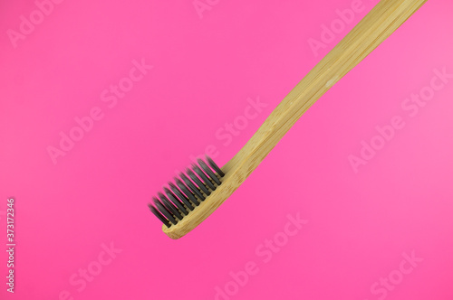 New bamboo toothbrush on pink background. Ecological and organic  no waste  no plastic. Copy space. 