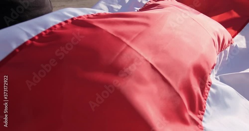 A man holds in his hands the unfolded flag of Belarus, which sways in the wind, close up. photo