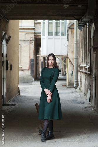 Stylish long-haired Girl in a long green dress is dancing in a shabby alleyway...Typical Petersburg courtyard