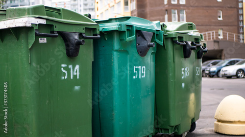 Green plastic garbage collection containers. In a row on the street