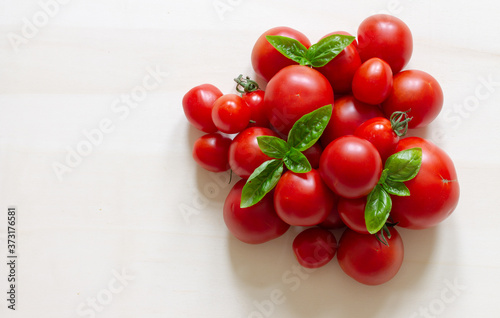 Tomatoes of different sizes on a light background. Place for text. Flat lay © Olena Siemer