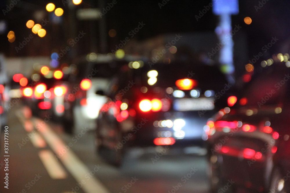 Automobiles with headlights and lights on in night city. Traffic jam in city