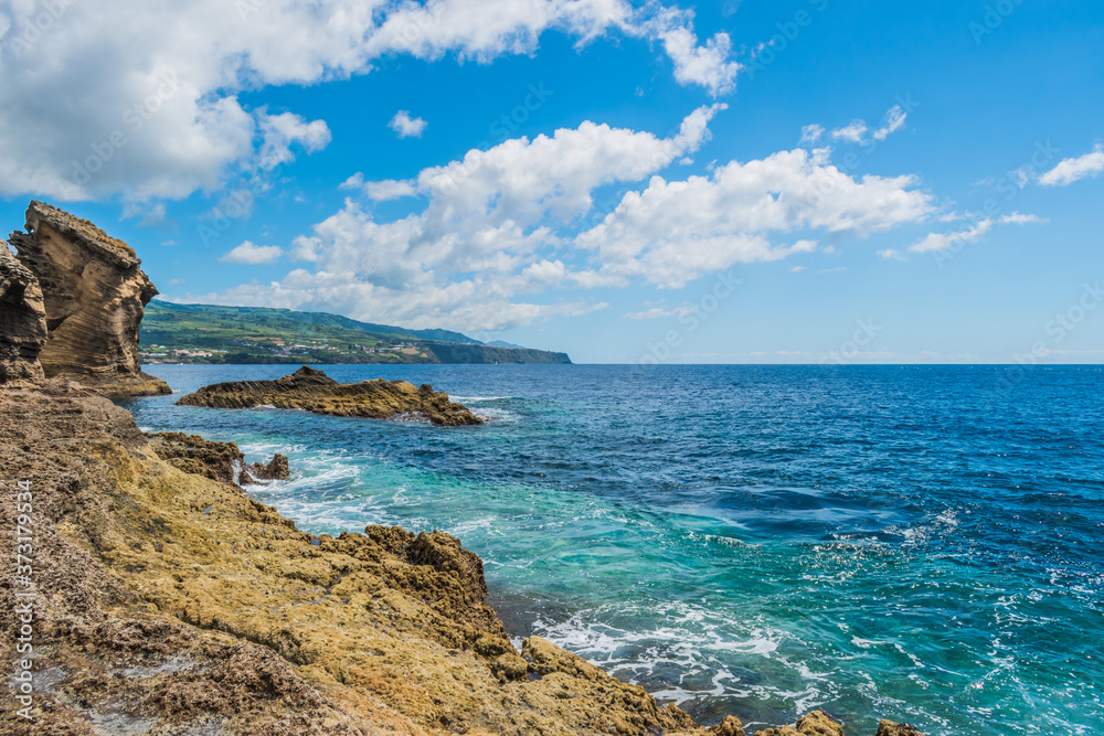 Landscape with volcanic rocks from the islet of Vila Franca with mountains of the island of São Miguel in the background and Atlantic Ocean, Azores PORTUGAL