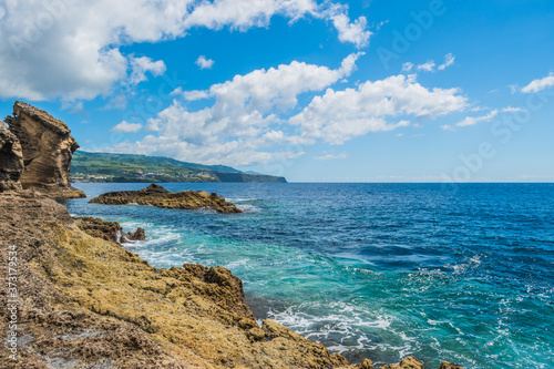 Landscape with volcanic rocks from the islet of Vila Franca with mountains of the island of São Miguel in the background and Atlantic Ocean, Azores PORTUGAL